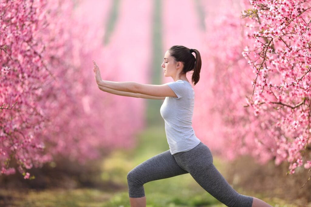 a woman doing yoga in a field of pink flowers - fertility yoga