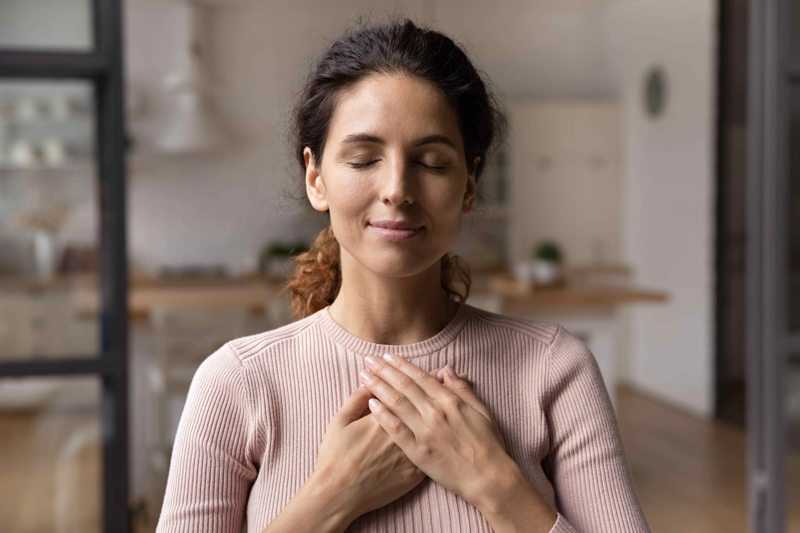 a woman with her eyes closed holding her hands on her chest