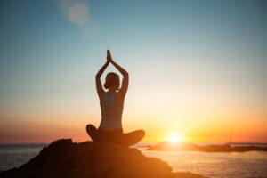 silhouette person practicing evening yoga on rock