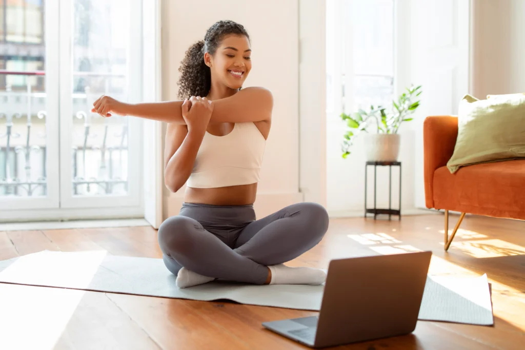 Woman stretching while using laptop